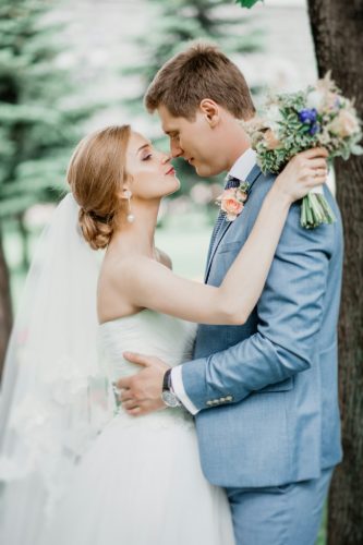 Bride smiling by window in lace gown
